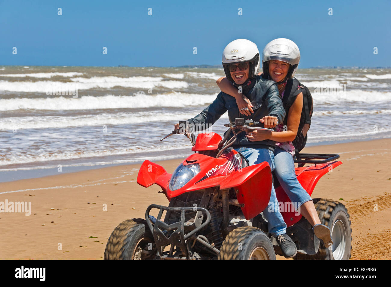 Ritratto orizzontale di un giovane uomo e donna su di una moto quad sulla spiaggia sul Marocco. Foto Stock