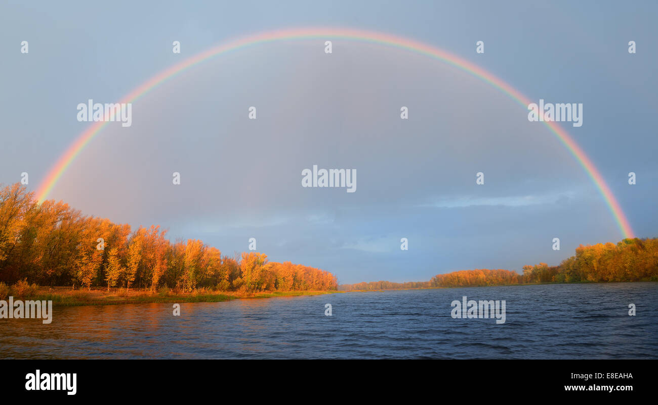 Rainbow oltre il fiume in autunno Foto Stock