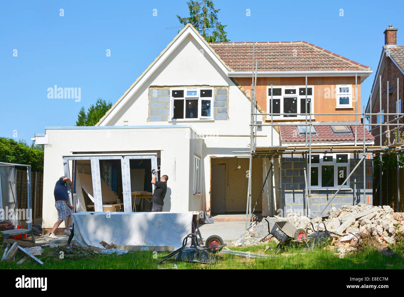 Operai installare UPVC fold back doors parte di maggiore estensione a casa unifamiliare Essex England Regno Unito (scaffold essendo rimosso) vedere 'More Info' nota di seguito Foto Stock