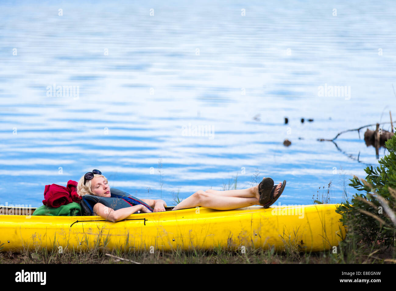 Stanco donna che dorme in un kayak giallo Foto Stock