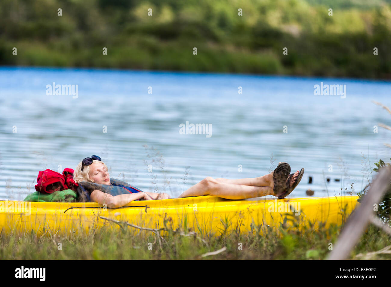 Stanco donna che dorme in un kayak giallo Foto Stock