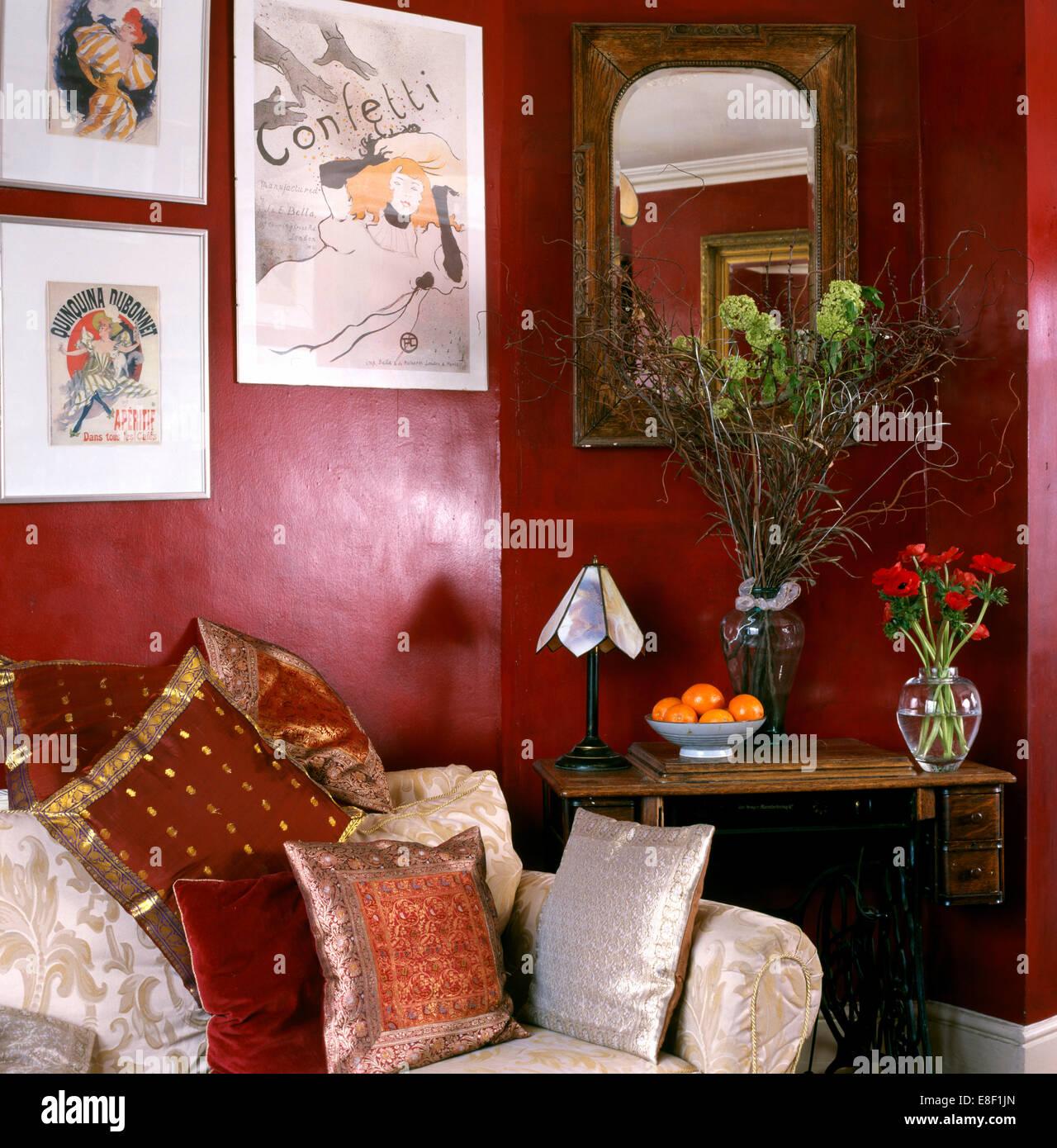 Foto sopra divano indiano con cuscini di seta in un angolo del salotto  rosso con pareti laccate e piccolo tavolo sotto lo specchio Foto stock -  Alamy