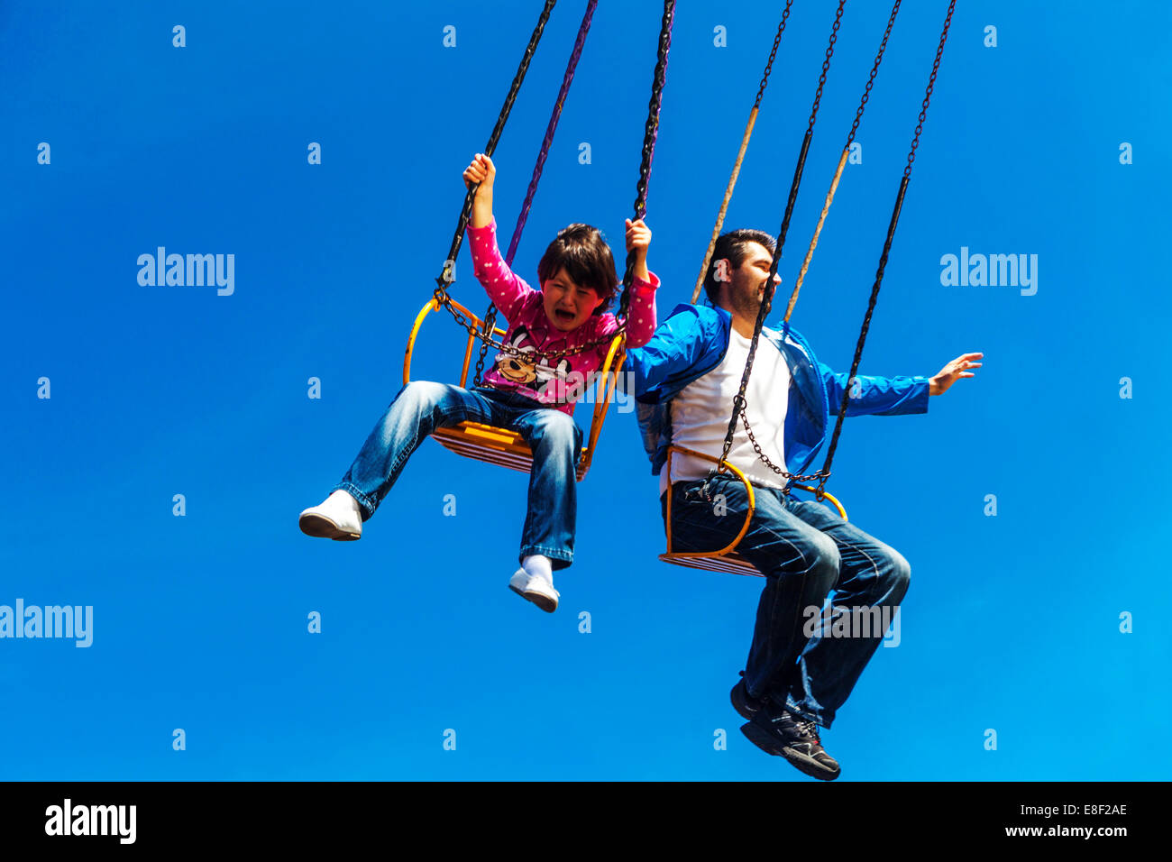 Persone su carousel ride, uomo bambino, padre e figlia, il bambino piange Foto Stock