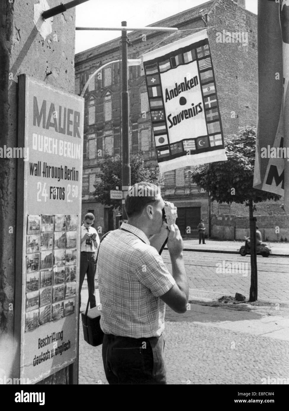 Un turista di fronte a un negozio di souvenir fotografie confine case in mattoni con finestre e porte in Bernauer Street il 13 agosto del 1961, esattamente un anno dopo l'inizio della costruzione del muro di Berlino. Foto Stock
