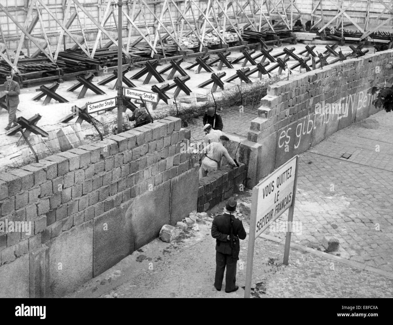 Muratori da Berlino Est, custodito dalla RDT soldati di confine, costruire parti del muro di Berlino in Bernauer Street il 26 di Maggio di 1962, che è crollato a causa di attentati alla bomba che notte. Foto Stock
