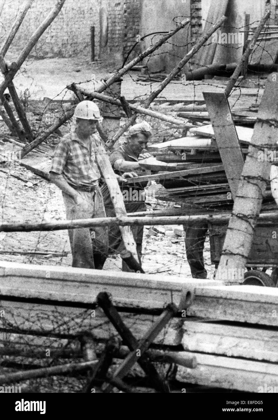 Una squadra di lavoro, in cui una donna partecipa, rinnova la parete in Bernauer Street il 23 agosto nel 1965. Foto Stock