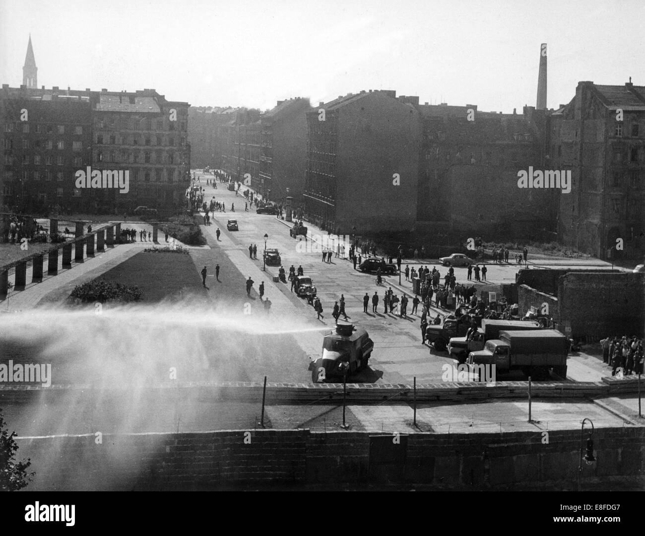 Camion e un cannone ad acqua può essere visto in azione in una strada laterale di Bernauer Street sul lato appartenenti a Berlino est, 24 settembre 1961. La gente di polizia della RDT ha iniziato con lo sfratto dei confinanti con case in Bernauer Street e tiro con gas lacrimogeni e acqua a guardare ad ovest i berlinesi, soprattutto gli operatori della fotocamera e fotografi. Dal 13 agosto 1961, il giorno della costruzione del muro di Berlino, alla caduta del muro di Berlino del 9 novembre 1989, la Repubblica federale di Germania e della Repubblica democratica tedesca sono stati separati dalla cortina di ferro tra Occidente e Oriente. Foto Stock