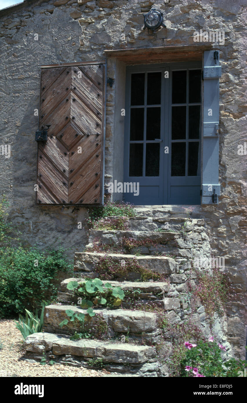Esterno della vecchia casa provenzale con gradini in pietra fino a porte Francesi con rustici persiane di legno Foto Stock