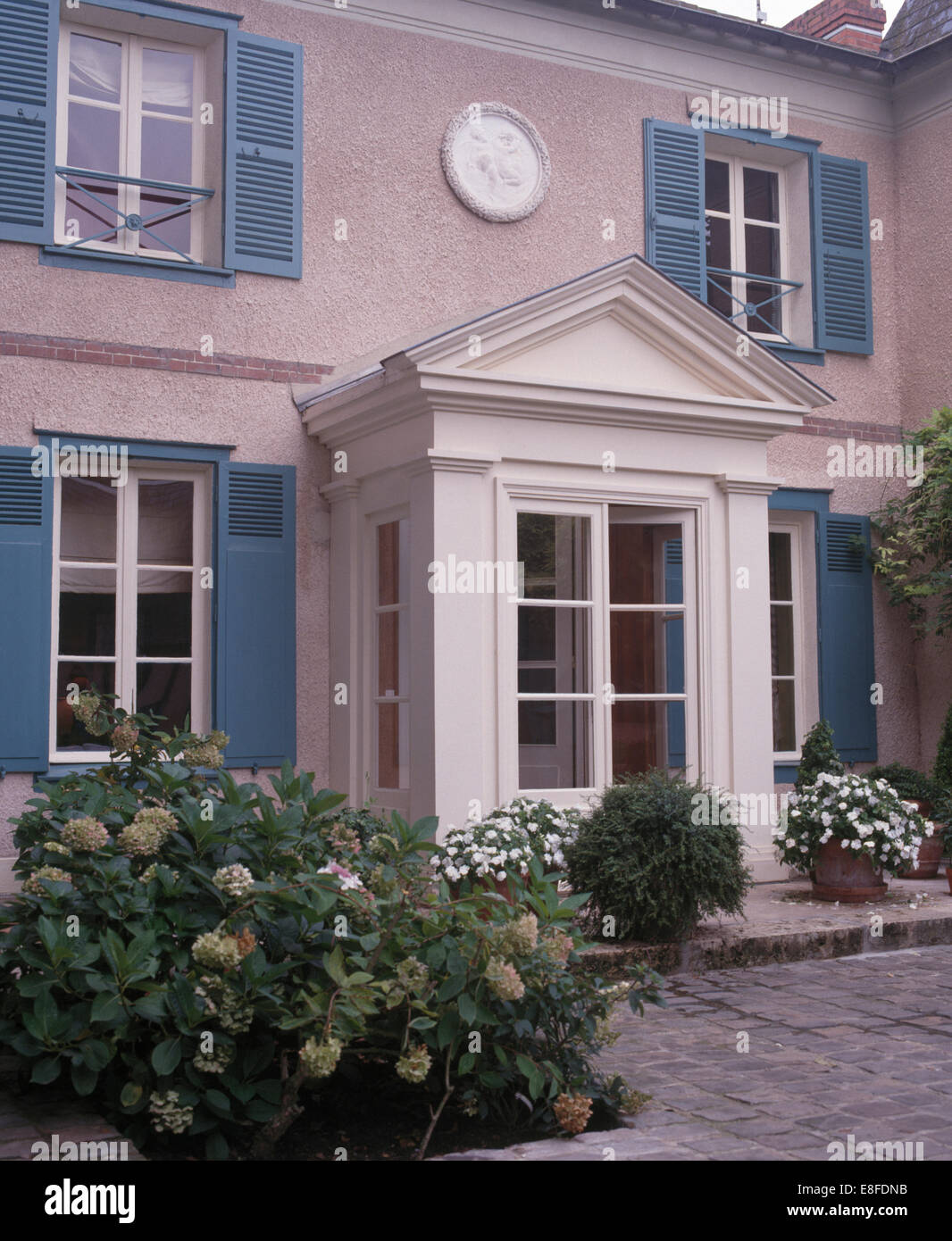 Impatiens bianco in vasi su entrambi i lati del portico di casa cittadina francese con persiane blu Foto Stock