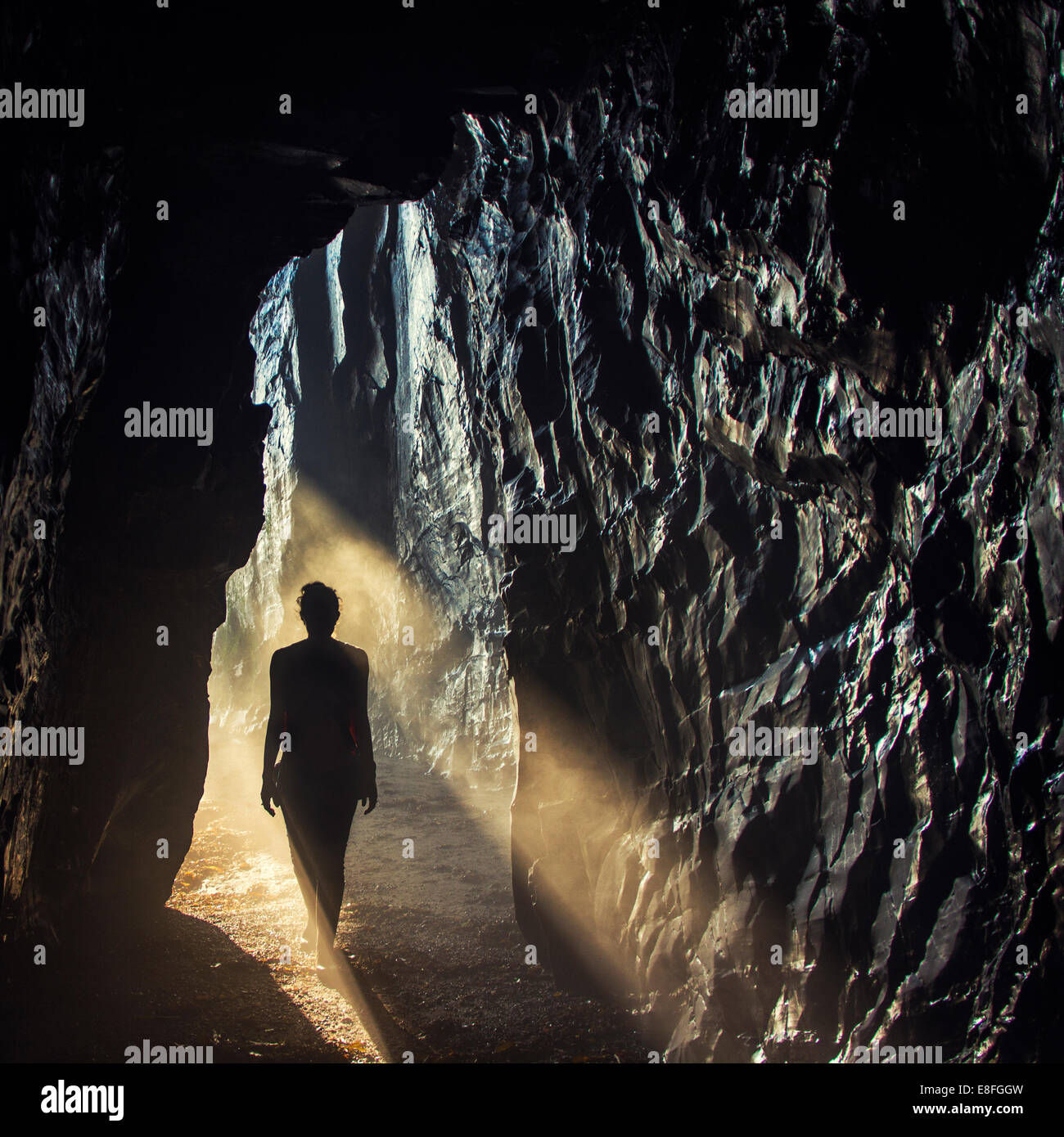 Silhouette di una donna che cammina in una grotta Foto Stock