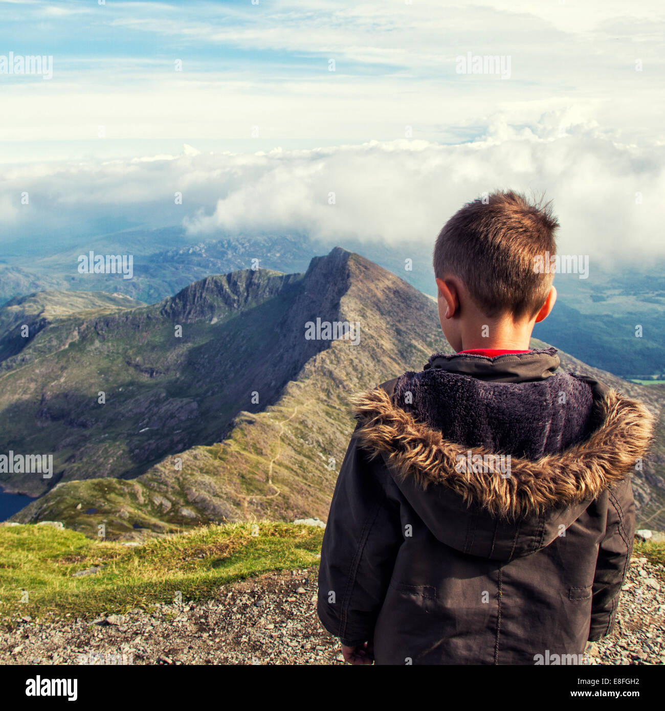 Vista posteriore di un ragazzo che guarda il paesaggio di montagna, Snowdonia, Galles, Regno Unito Foto Stock