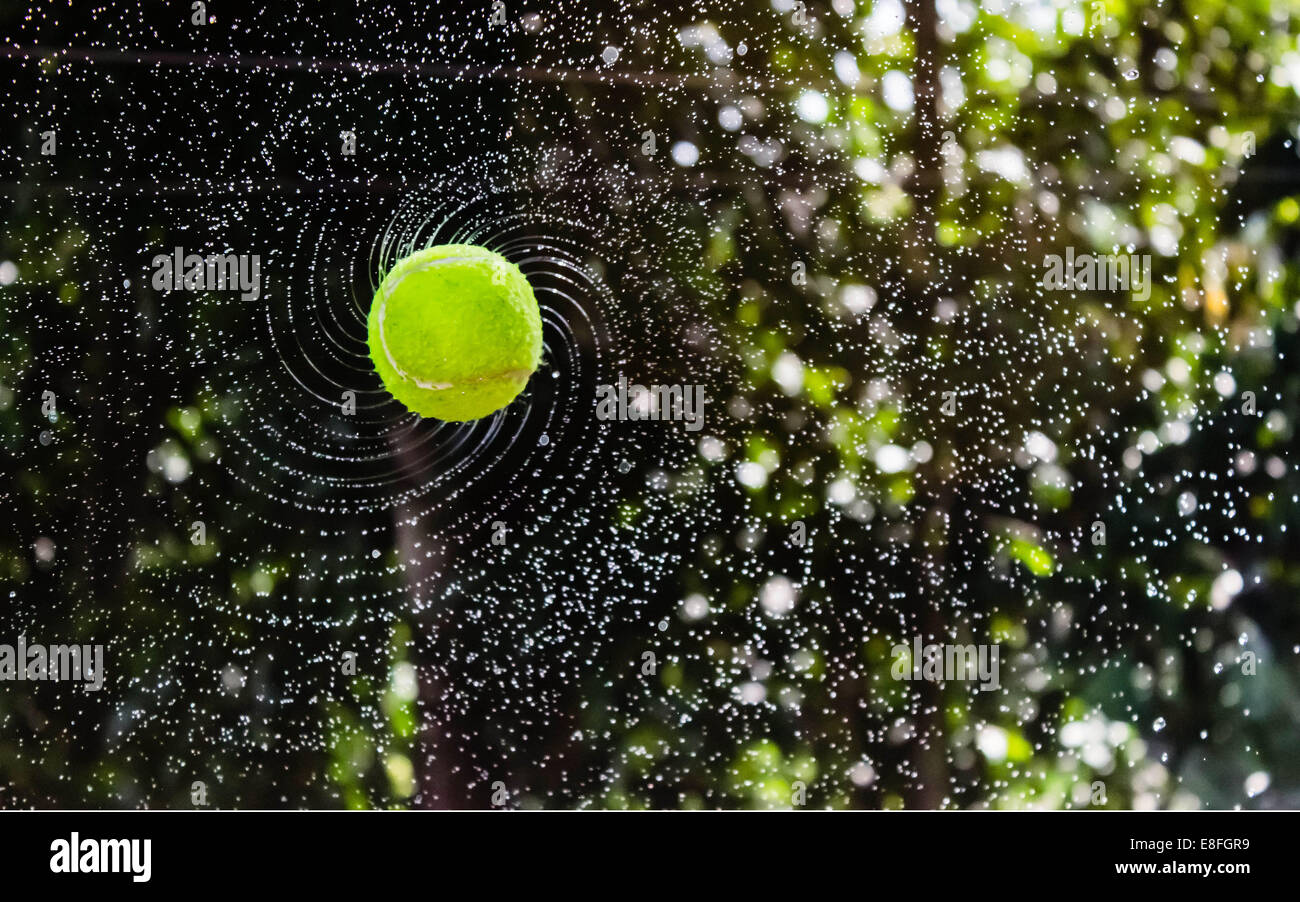Palla da tennis bagnata che vola in aria Foto Stock