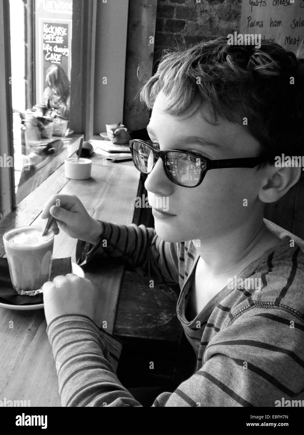 Ragazzo seduto in un bar a bere cioccolata calda Foto Stock
