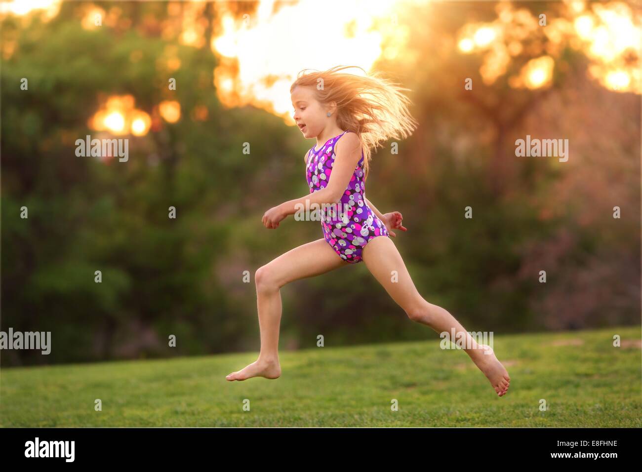 Ragazza che indossa un costume da bagno che corre nel giardino, California, Stati Uniti Foto Stock