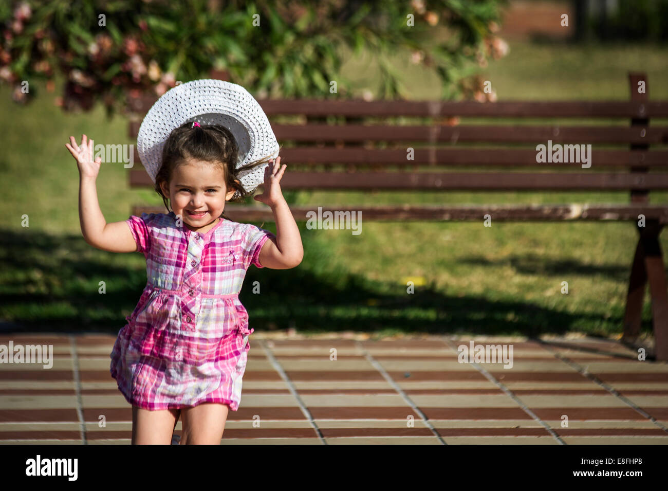 Ragazza che corre all'aperto con il vento che soffia hat off la sua testa Foto Stock