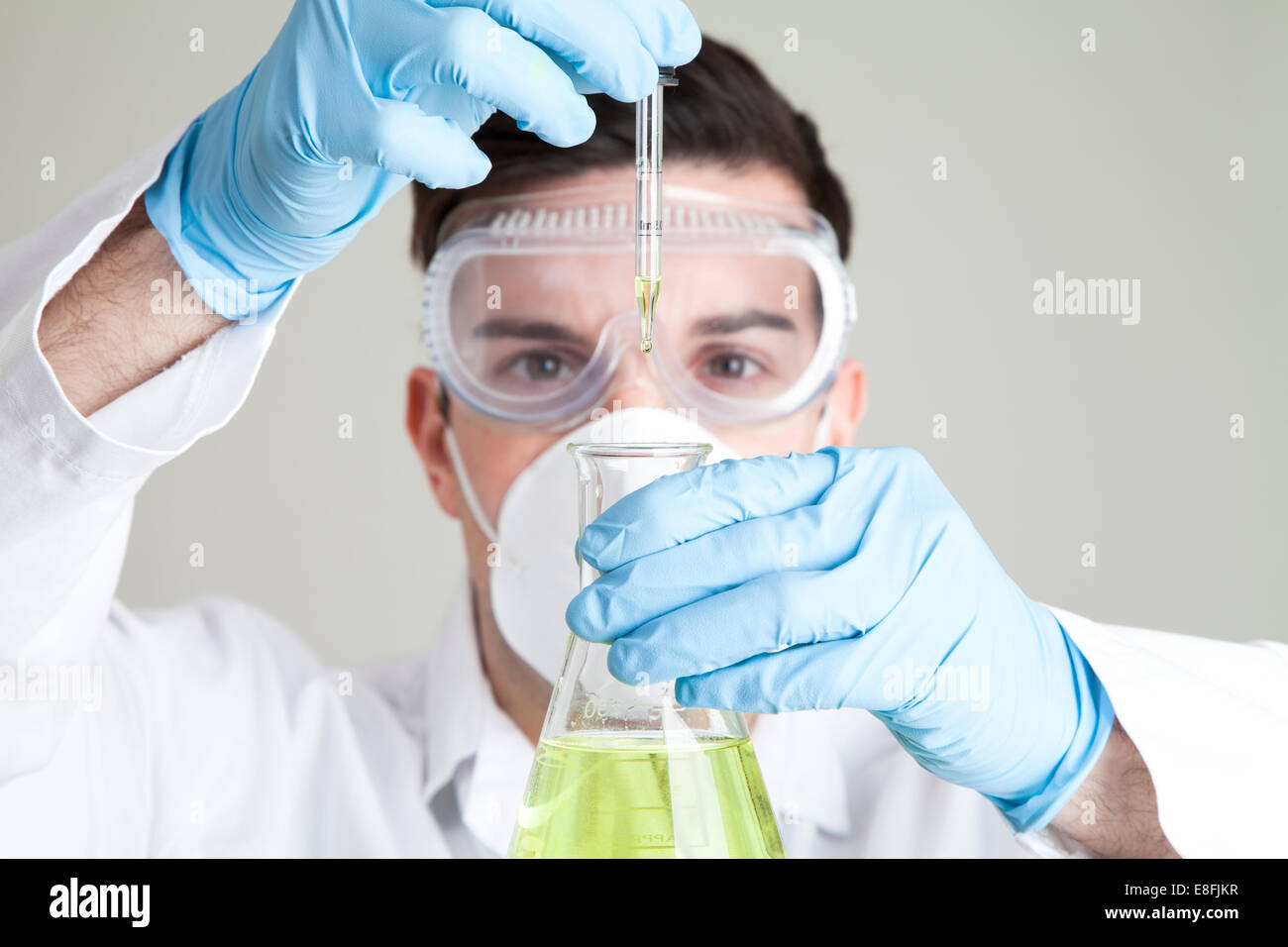 Scienziato tenendo una pipetta e matraccio conico Foto Stock