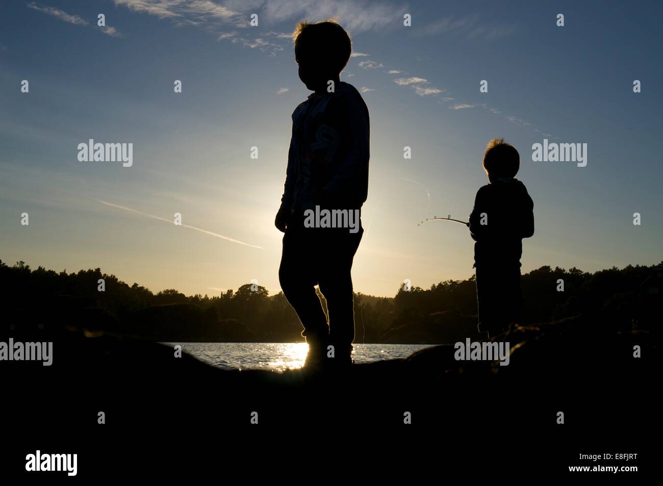 Silhouette di due ragazzi la pesca al tramonto, Tromoy, Arendal, Norvegia Foto Stock