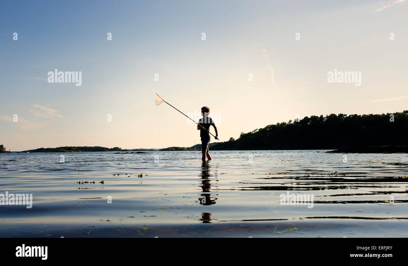 Silhouette di un ragazzo di pesca al tramonto, Tromoy, Arendal, Norvegia Foto Stock