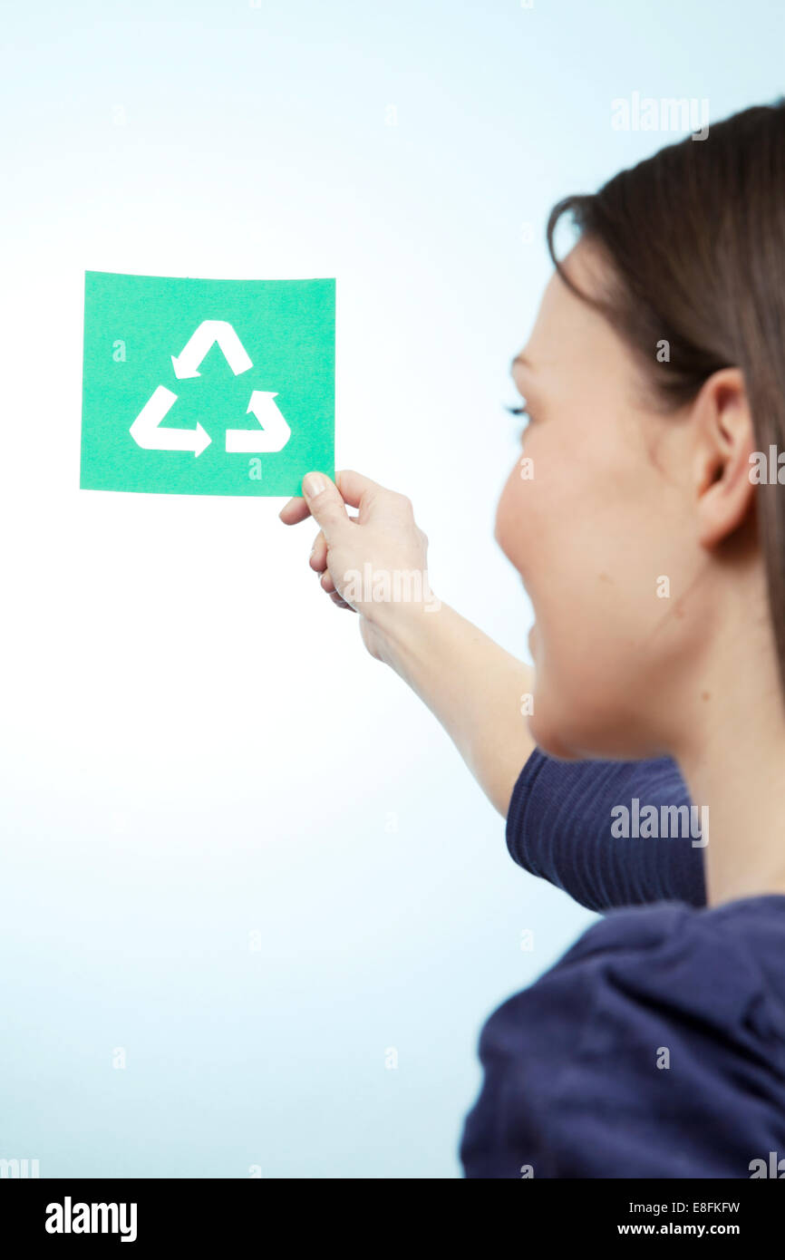 Donna che mantiene la carta tagliata del simbolo di riciclaggio Foto Stock