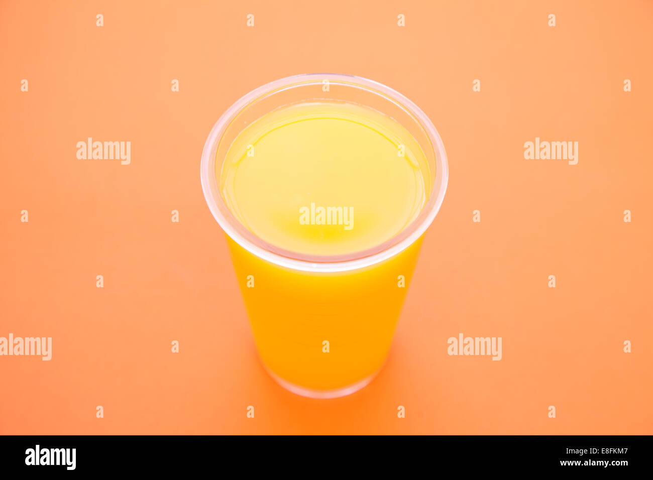 Bicchiere di succo d'arancia in una tazza usa e getta su sfondo arancione Foto Stock