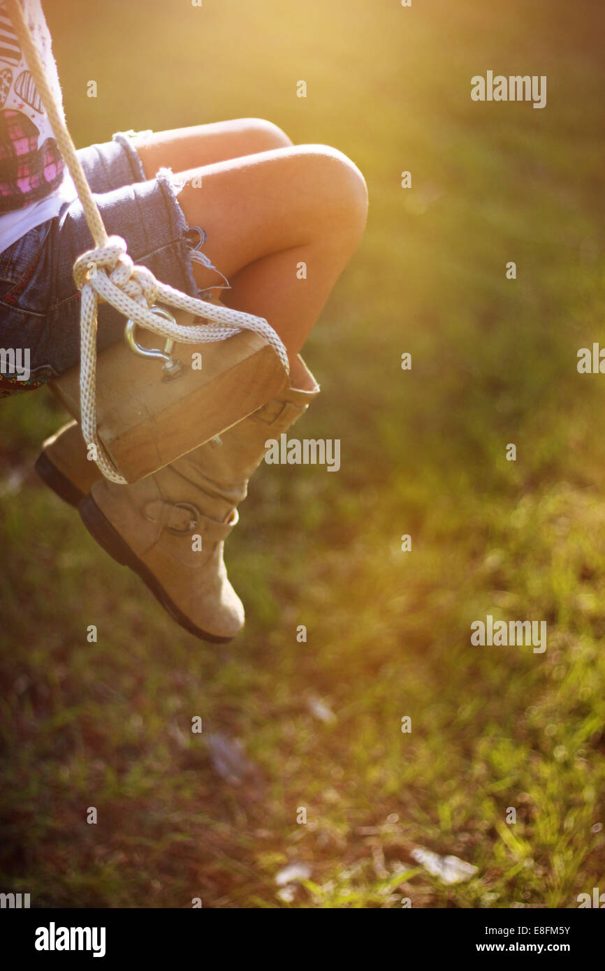 Primo piano delle gambe di una ragazza seduta su un'oscillazione di corda nel giardino, Mississippi, Stati Uniti Foto Stock