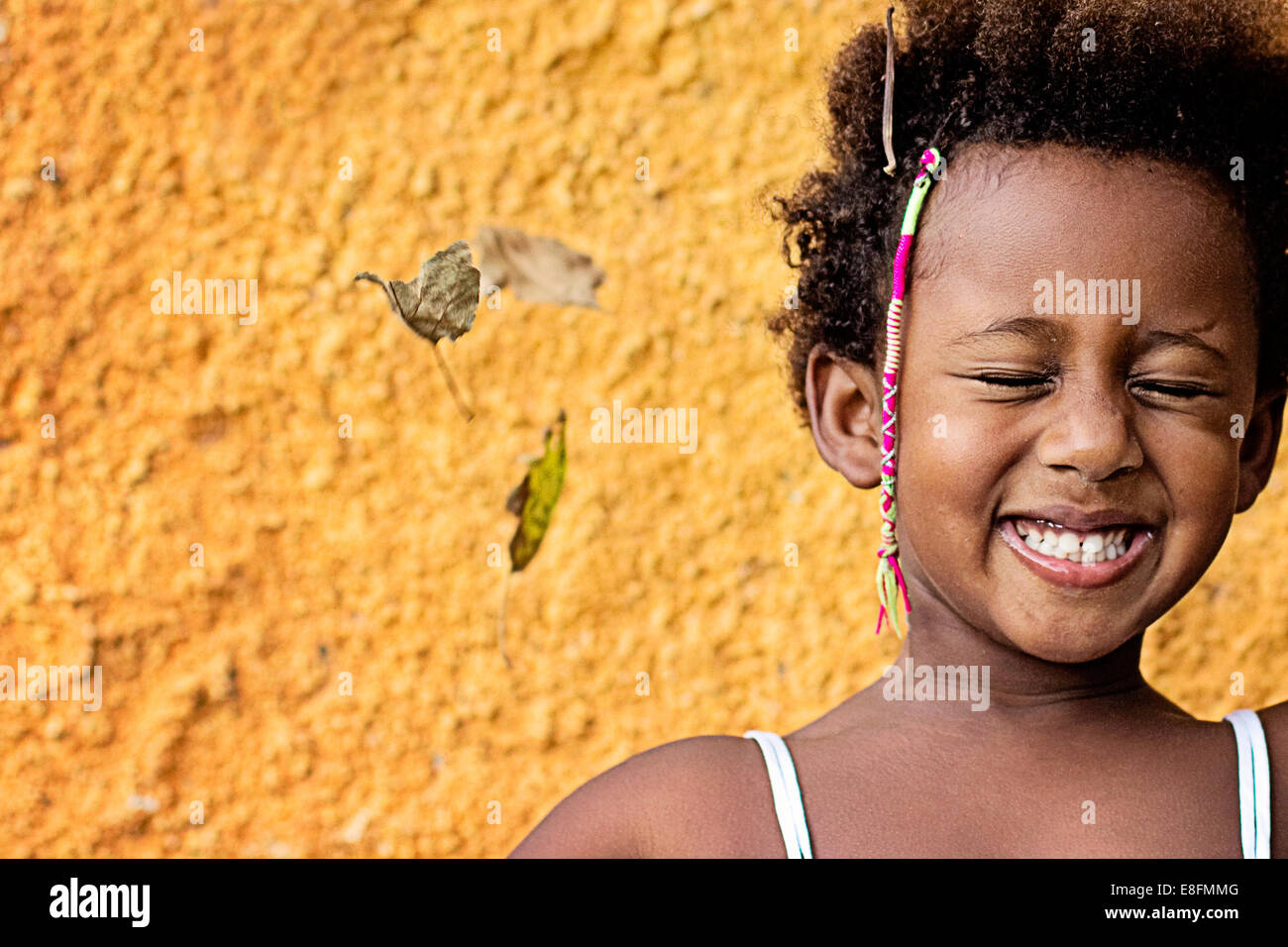 Ritratto di una ragazza sorridente in piedi contro la parete gialla Foto Stock