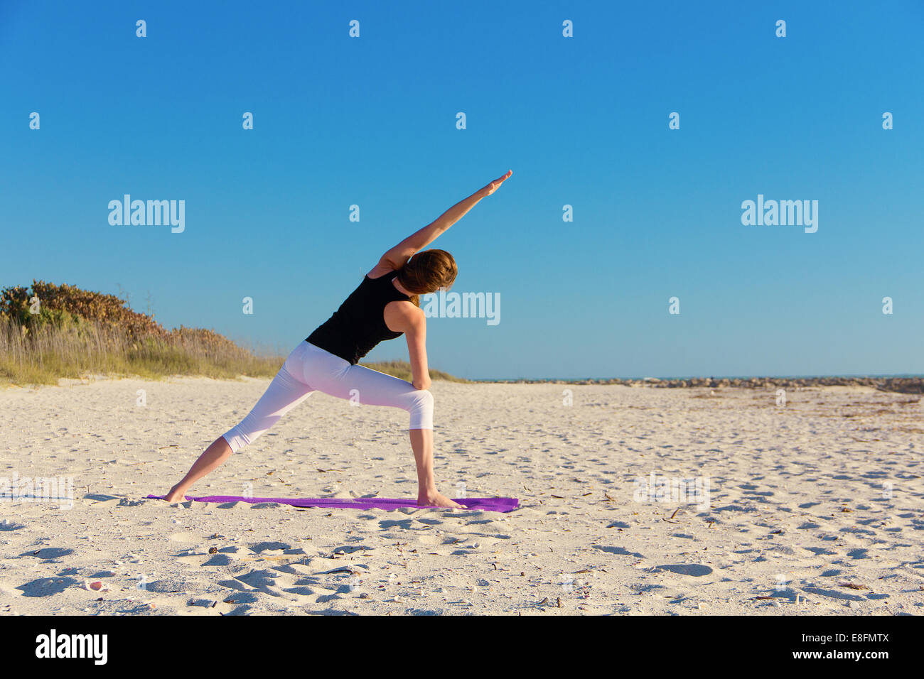 Vista posteriore della donna fare yoga sulla spiaggia Foto Stock
