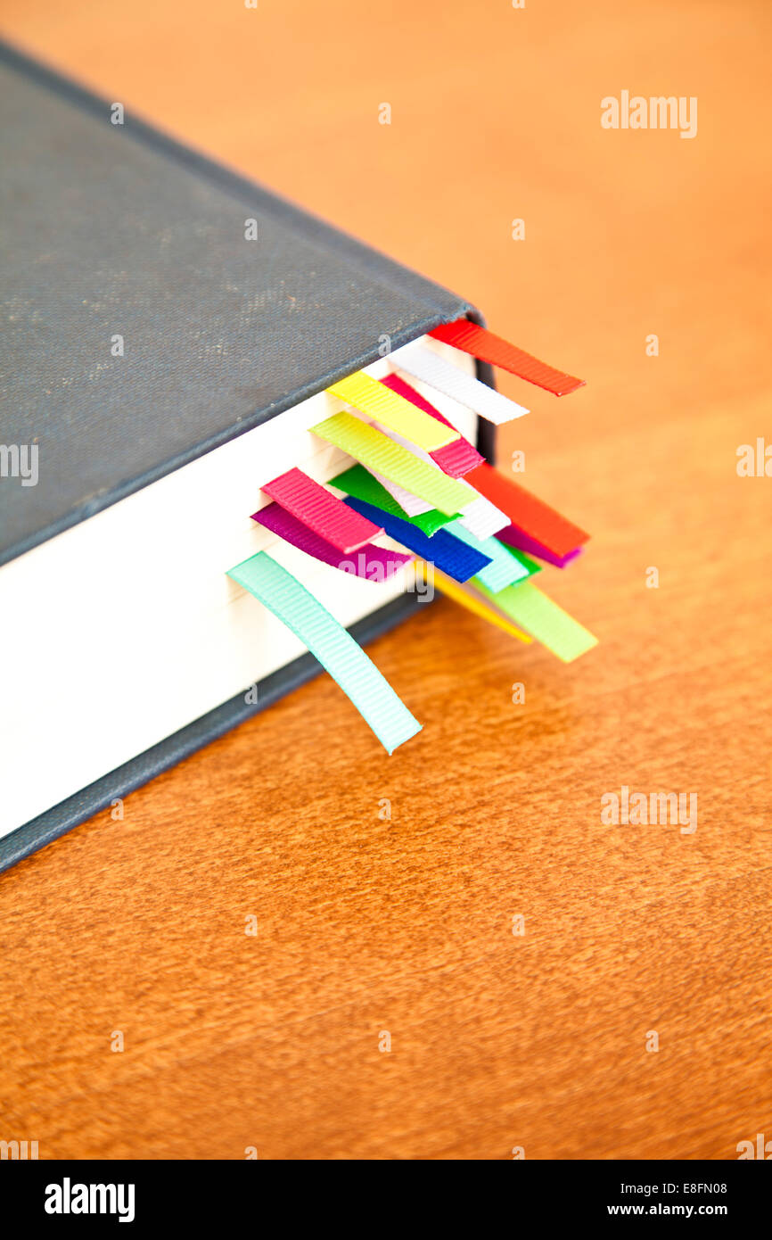 Primo piano di un libro hardback su un tavolo con segnalibri multicolore Foto Stock