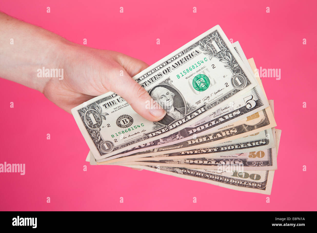 Primo piano della mano di una persona che detiene cinque banconote in dollari USA Foto Stock