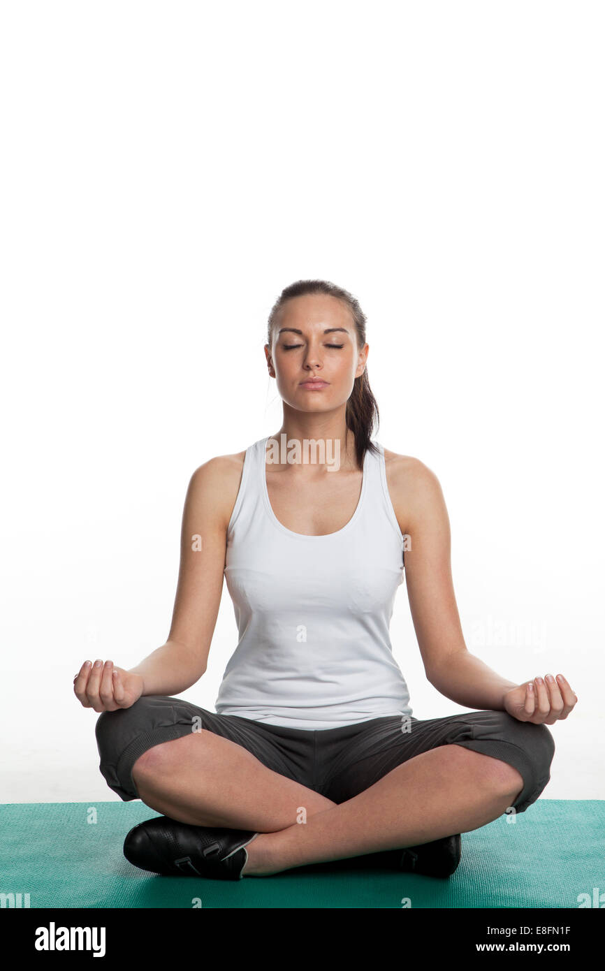 Giovane donna seduta yoga in posizione del loto Foto Stock