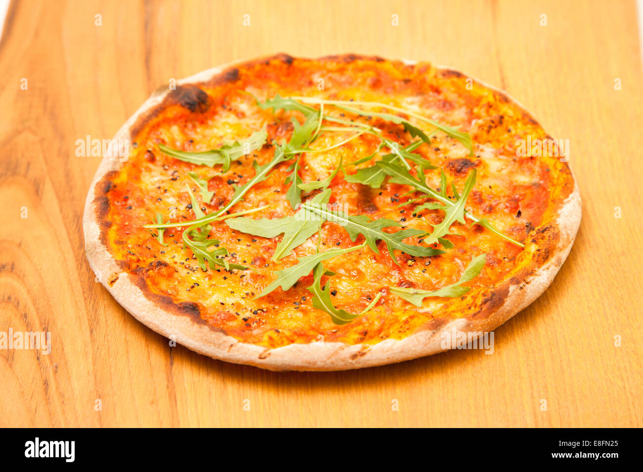 Pizza al formaggio e pomodoro con peperoncino e rucola su un tavolo di legno Foto Stock