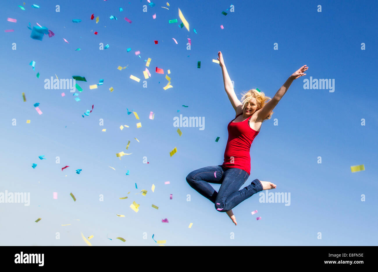 Giovane donna salta con coriandoli Foto Stock