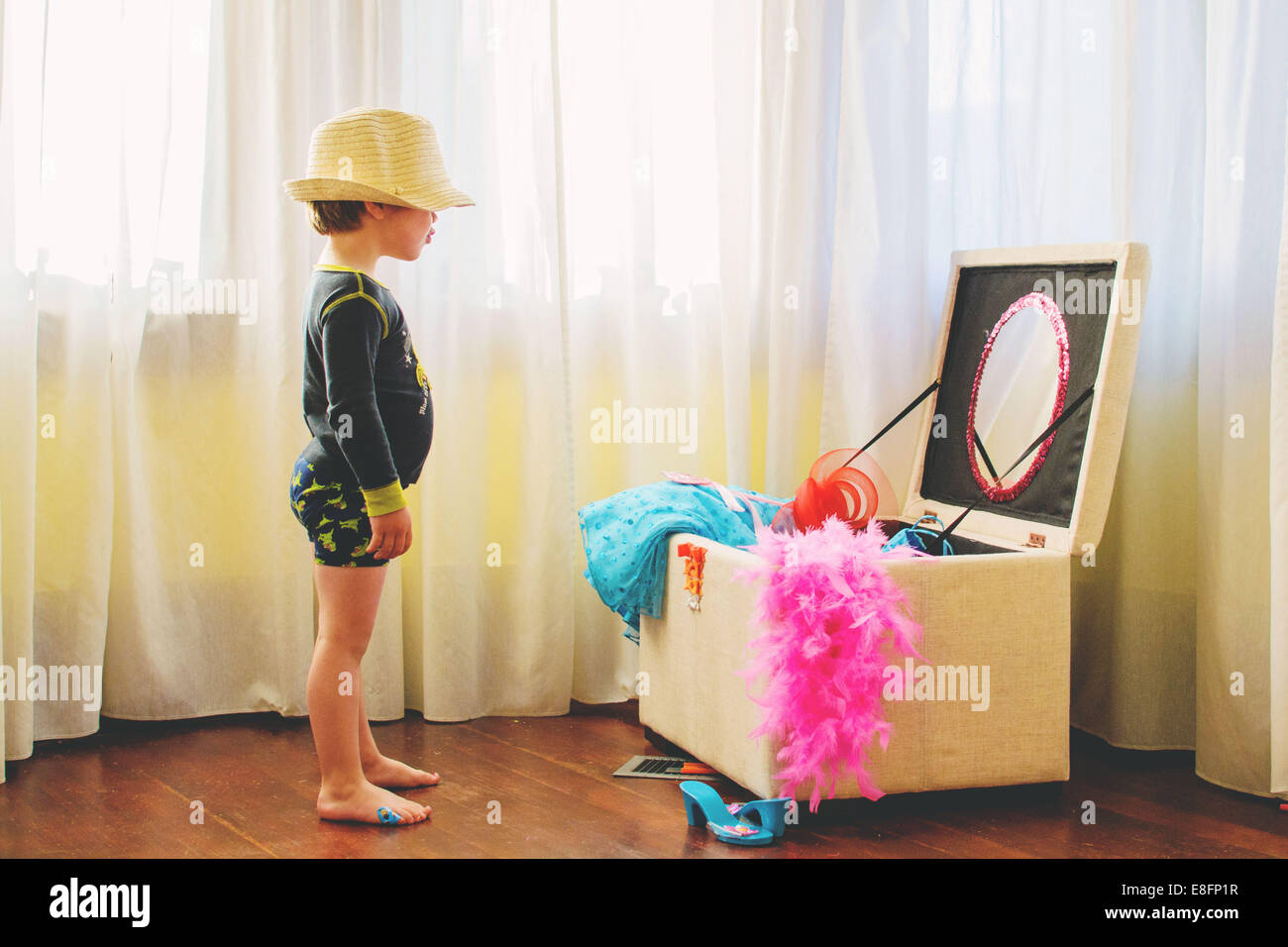 Ragazzo che indossa un cappello in piedi vestendo in su scatola Foto Stock