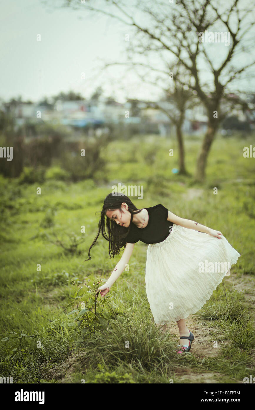 Il Vietnam, Hai Phong, ragazza (8-9) di raggiungere per le piante Foto Stock