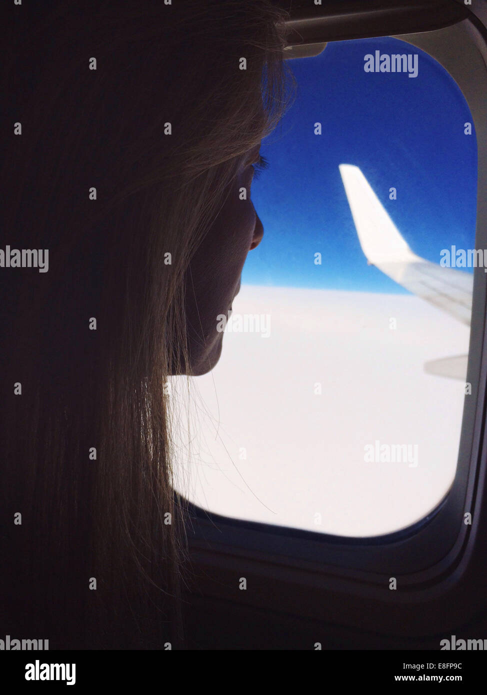 Donna che guarda fuori della finestra su un piano Foto Stock