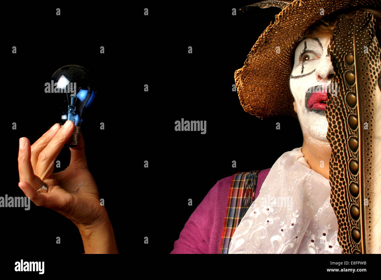 Clown femmina che tiene una lampadina e piuma Foto Stock