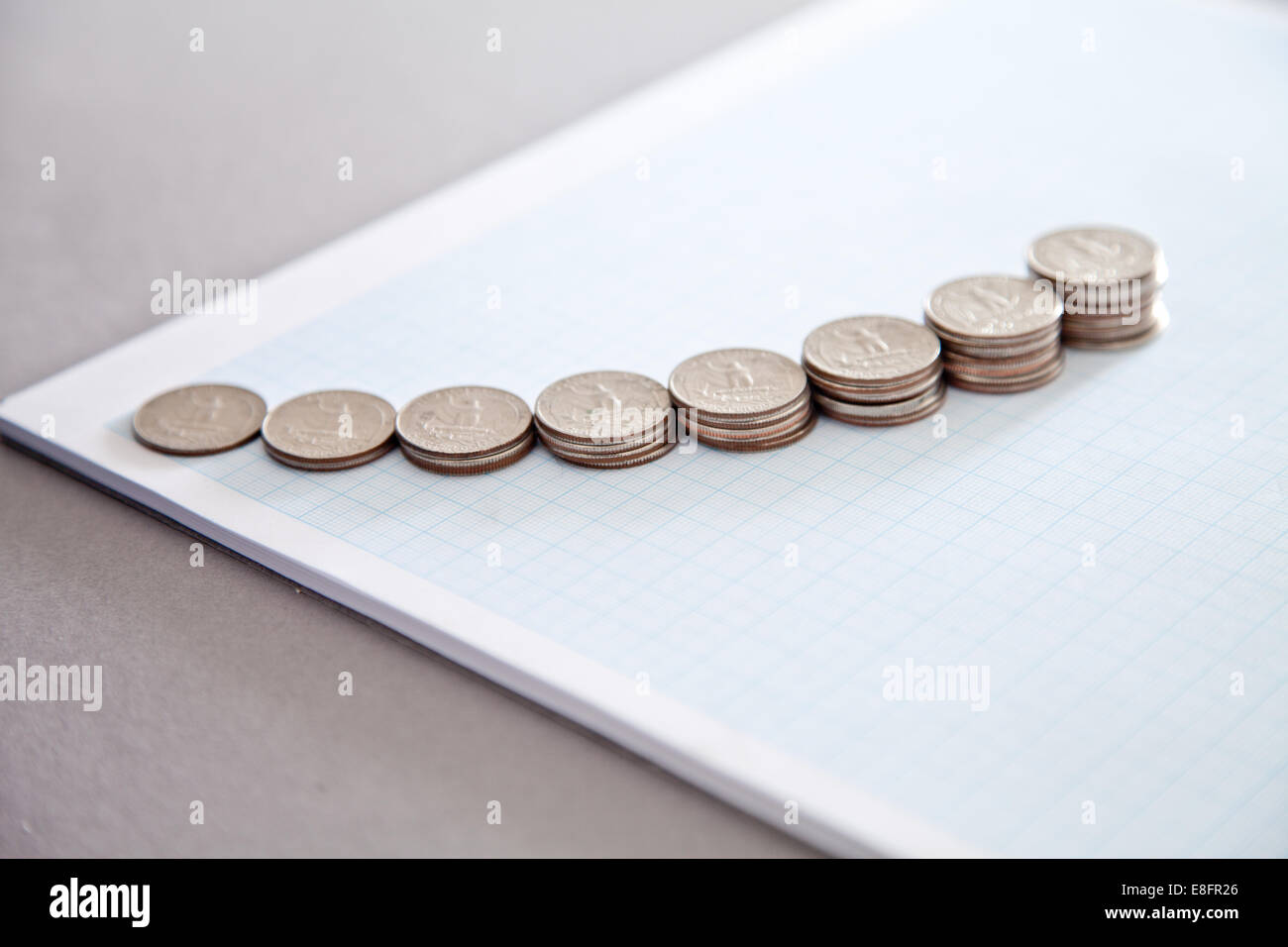 Più pile di monete statunitensi su un foglio di carta millimetrata Foto Stock