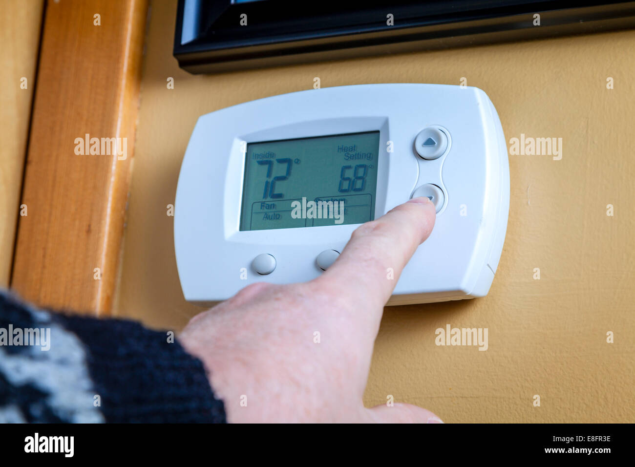 Una persona si abbassa la temperatura su un termostato di casa. Enegry concetto di risparmio Foto Stock