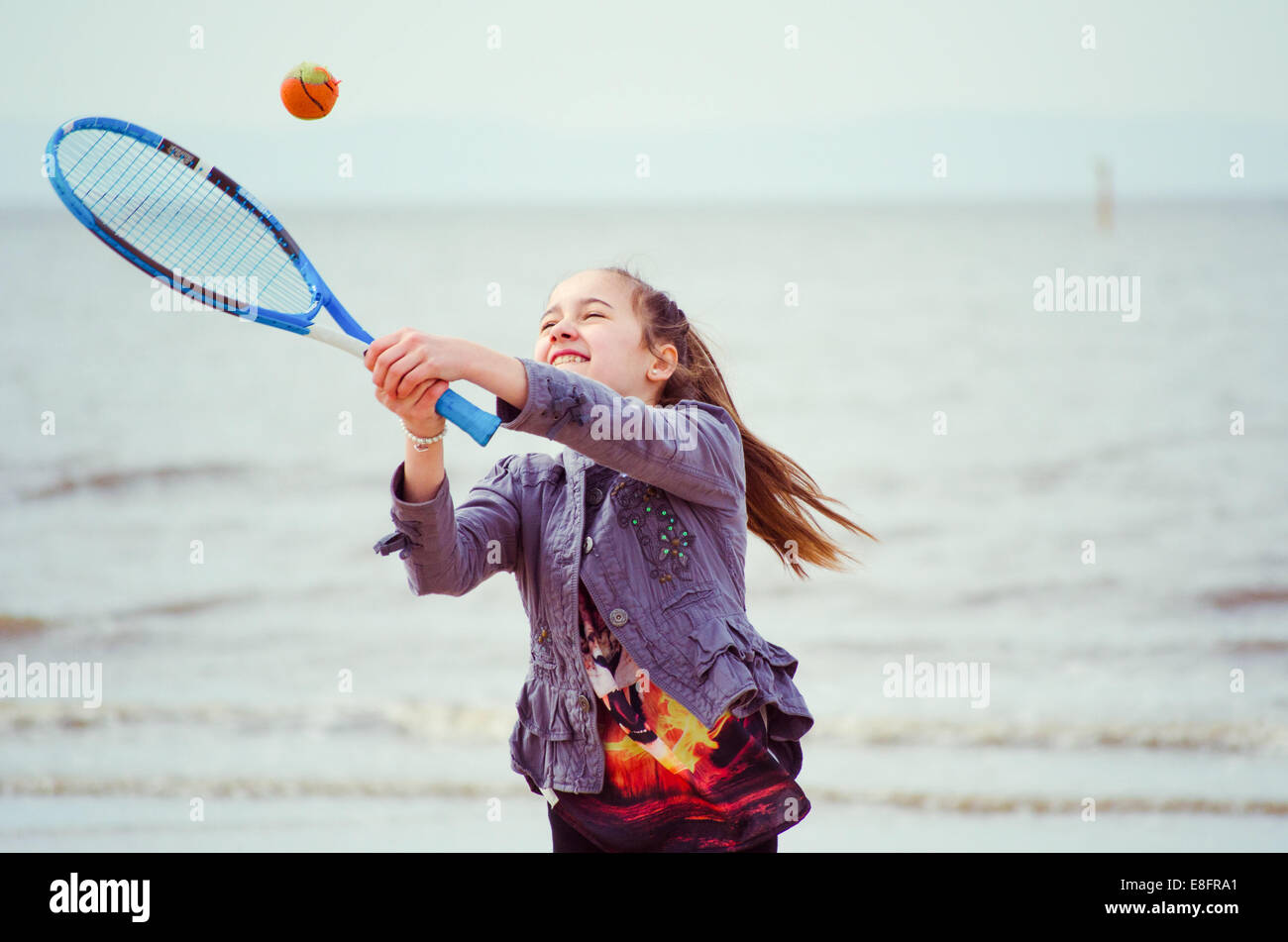 Ragazza giocando a tennis sulla spiaggia Foto Stock