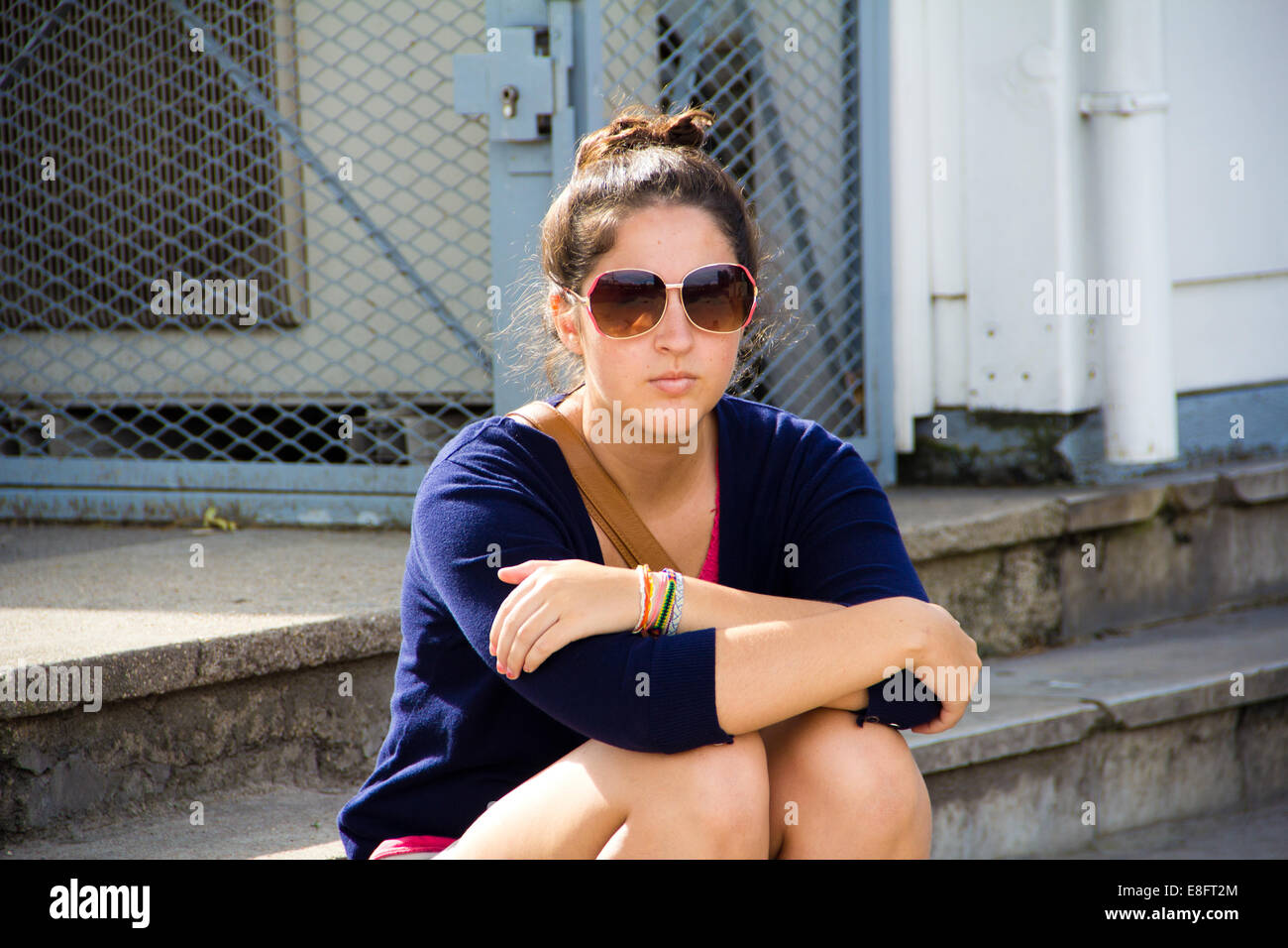Donna che indossa gli occhiali da sole seduto su una fase Foto Stock