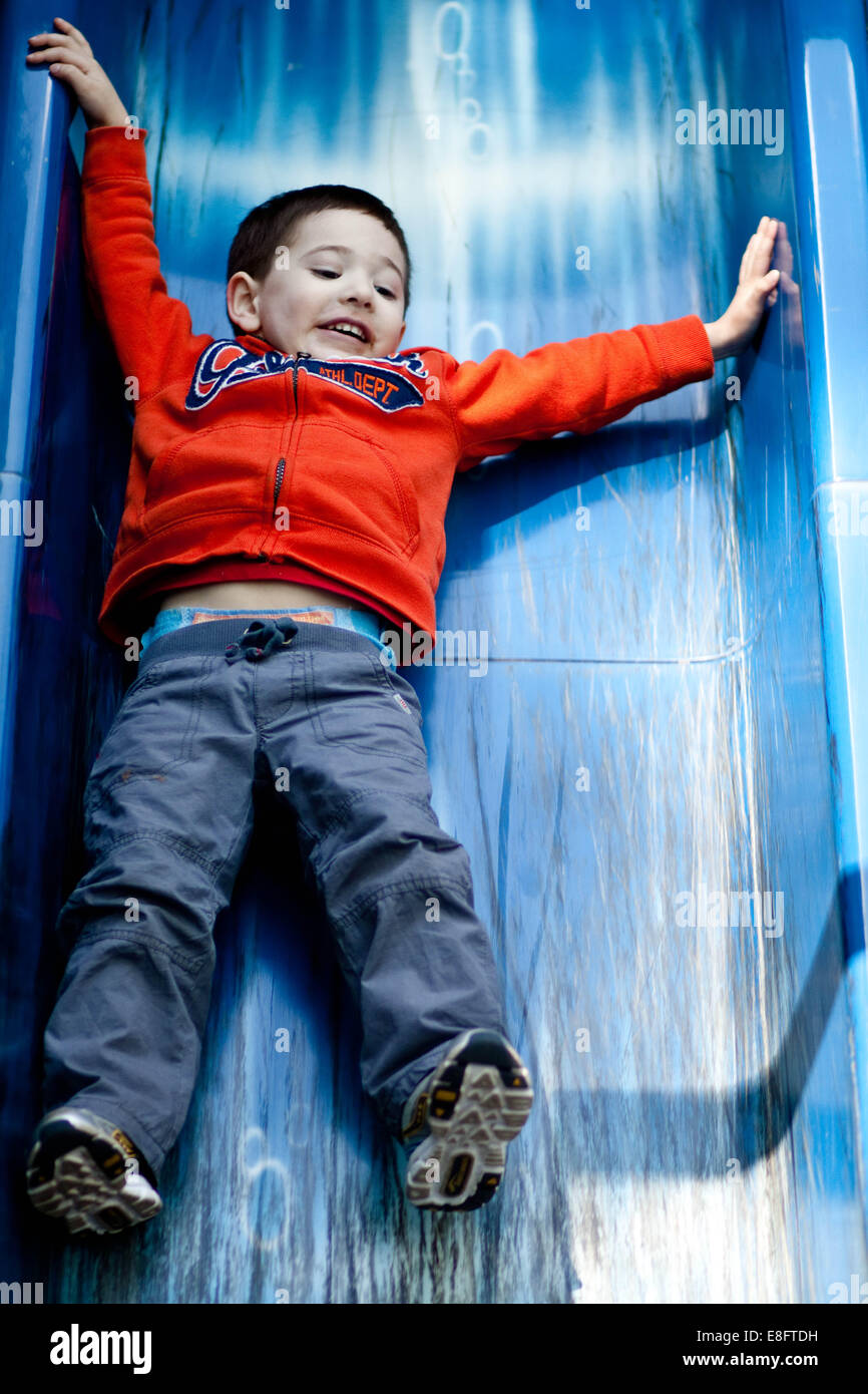 Ragazzo scivolare giù scorrere nel parco giochi Foto Stock