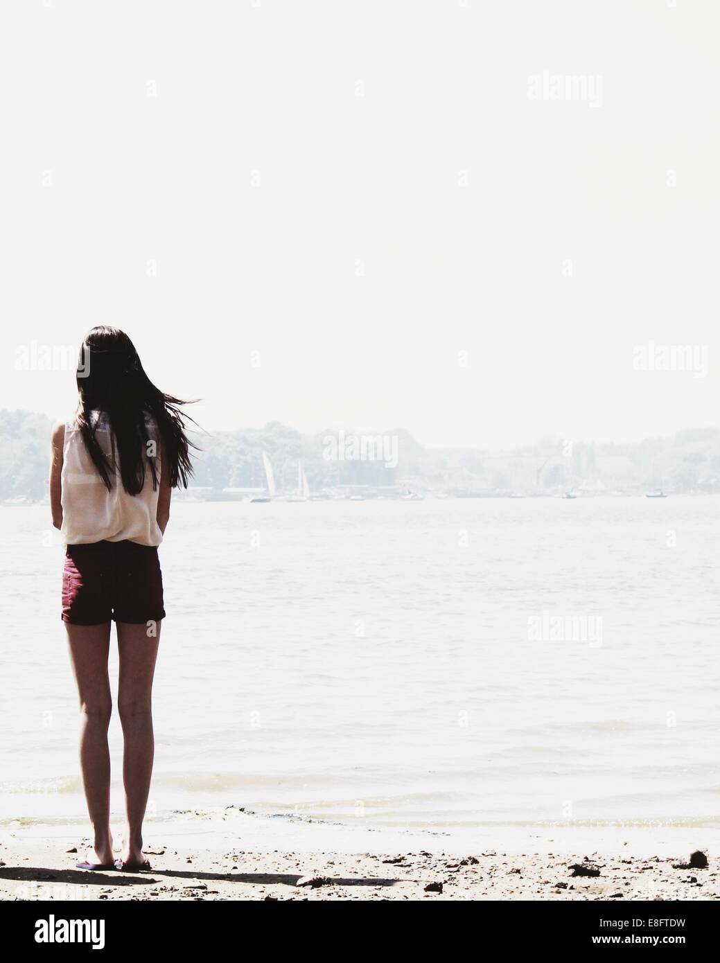 Vista posteriore della ragazza adolescente permanente sulla spiaggia cercando di visualizzare Foto Stock