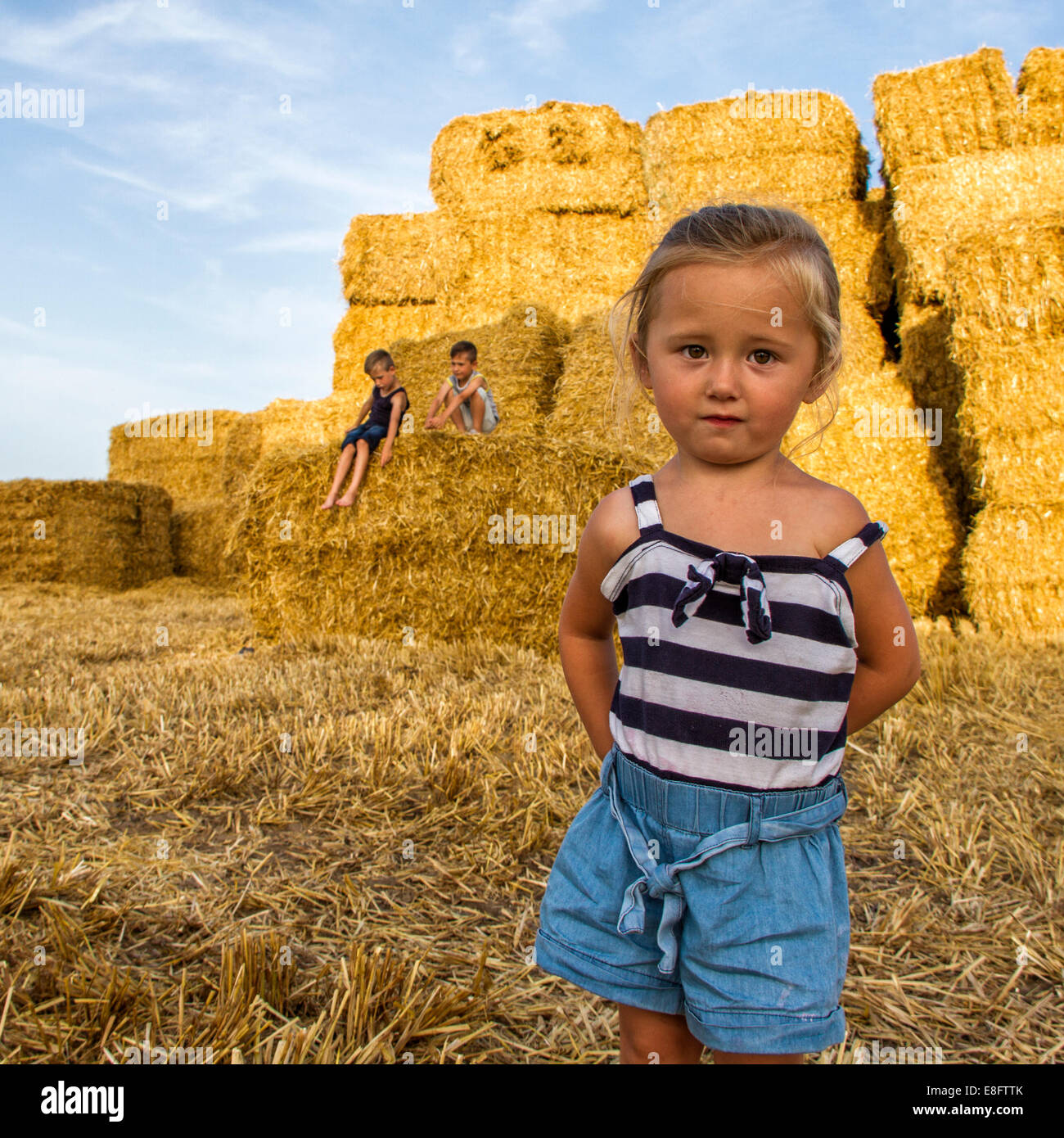 Tre bambini che giocano in un campo di balle di fieno, Inghilterra, Regno Unito Foto Stock