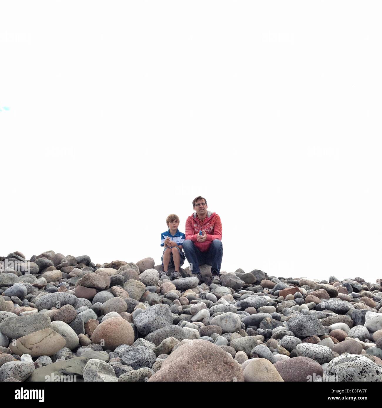 Padre e figlio seduti sulla spiaggia, Norvegia Foto Stock