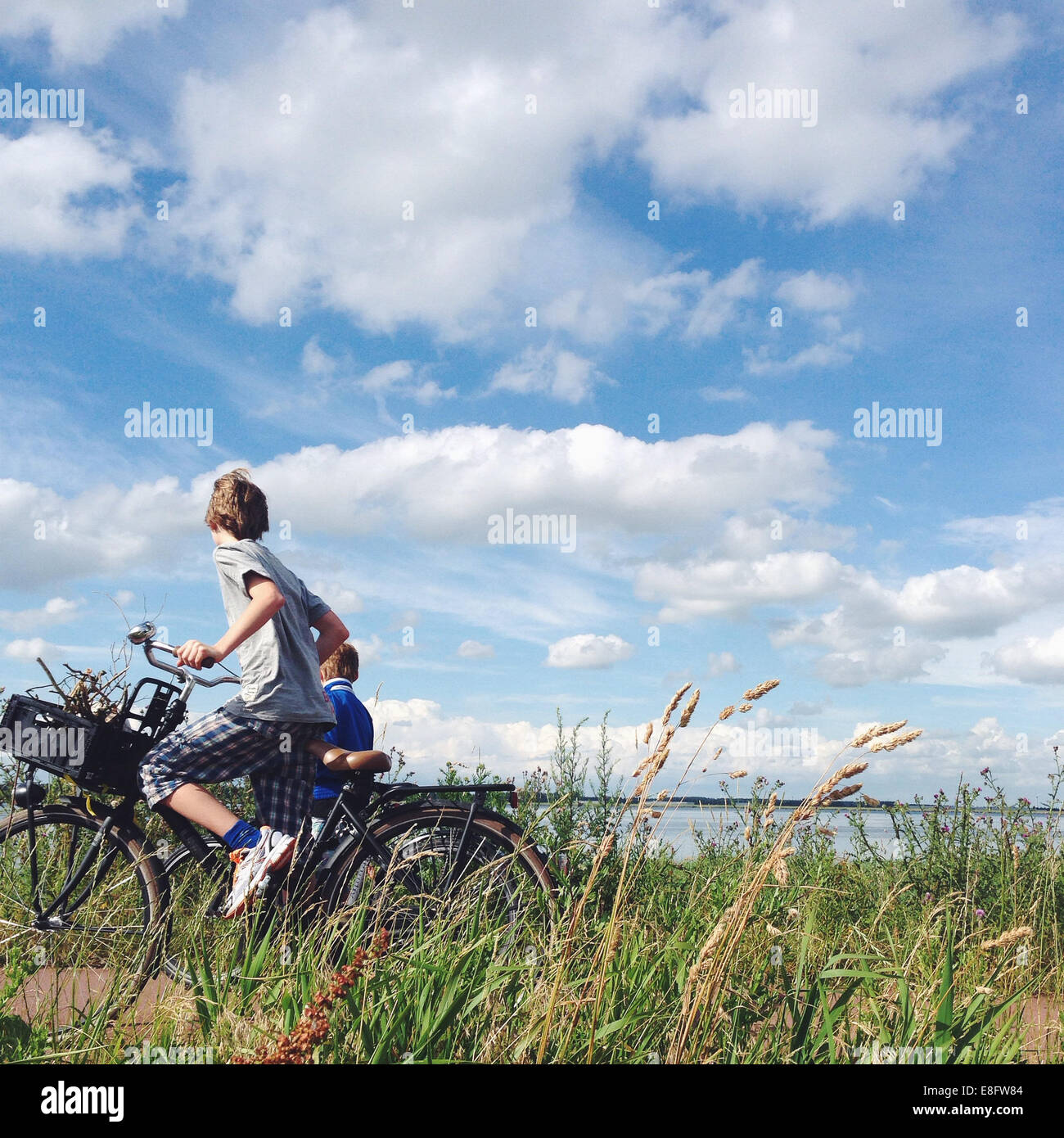 Due ragazzi in bicicletta su una diga sul mare, Olanda Foto Stock