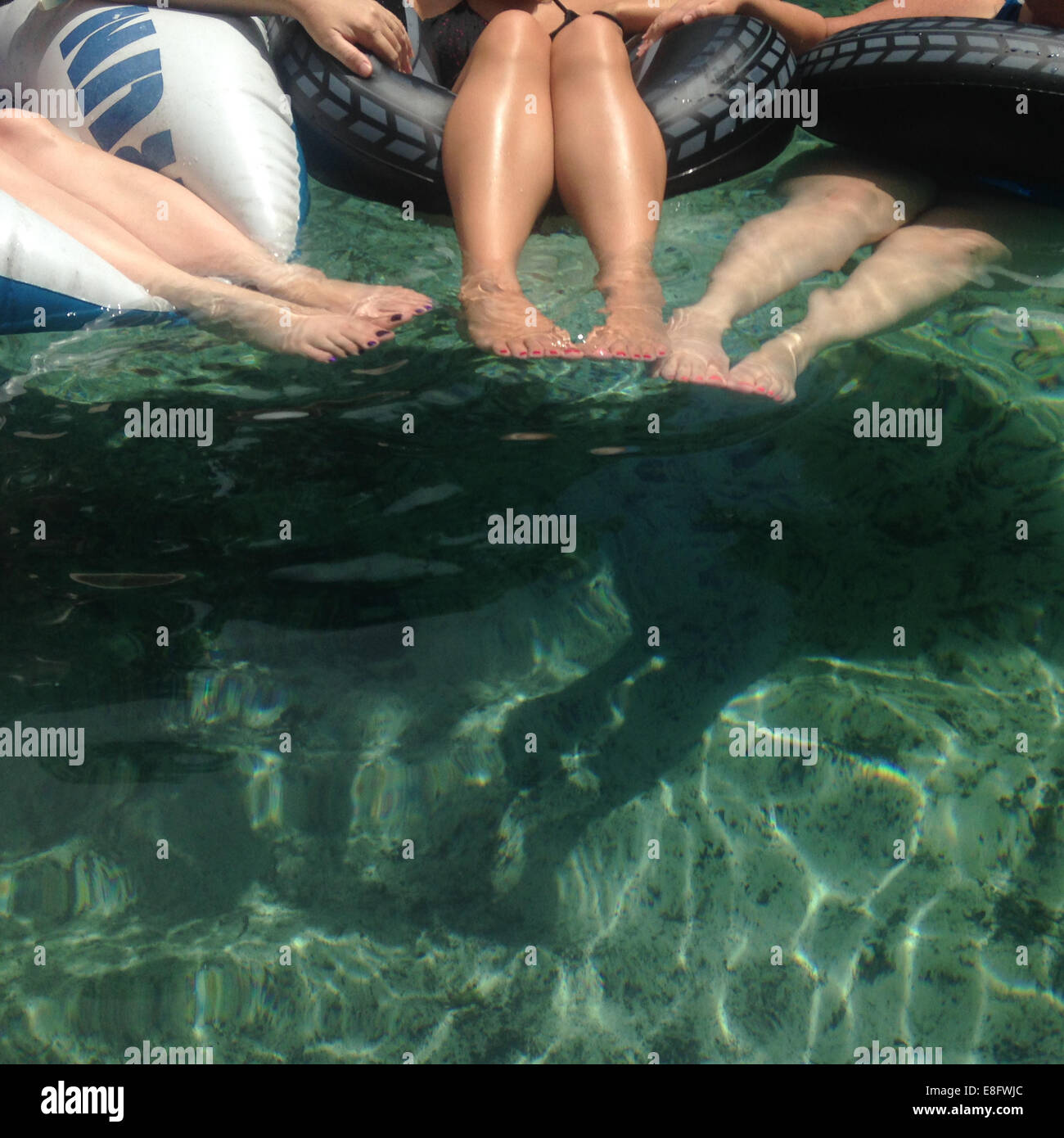 Tre donne sedute in anelli di gomma gonfiabili in una piscina Foto Stock