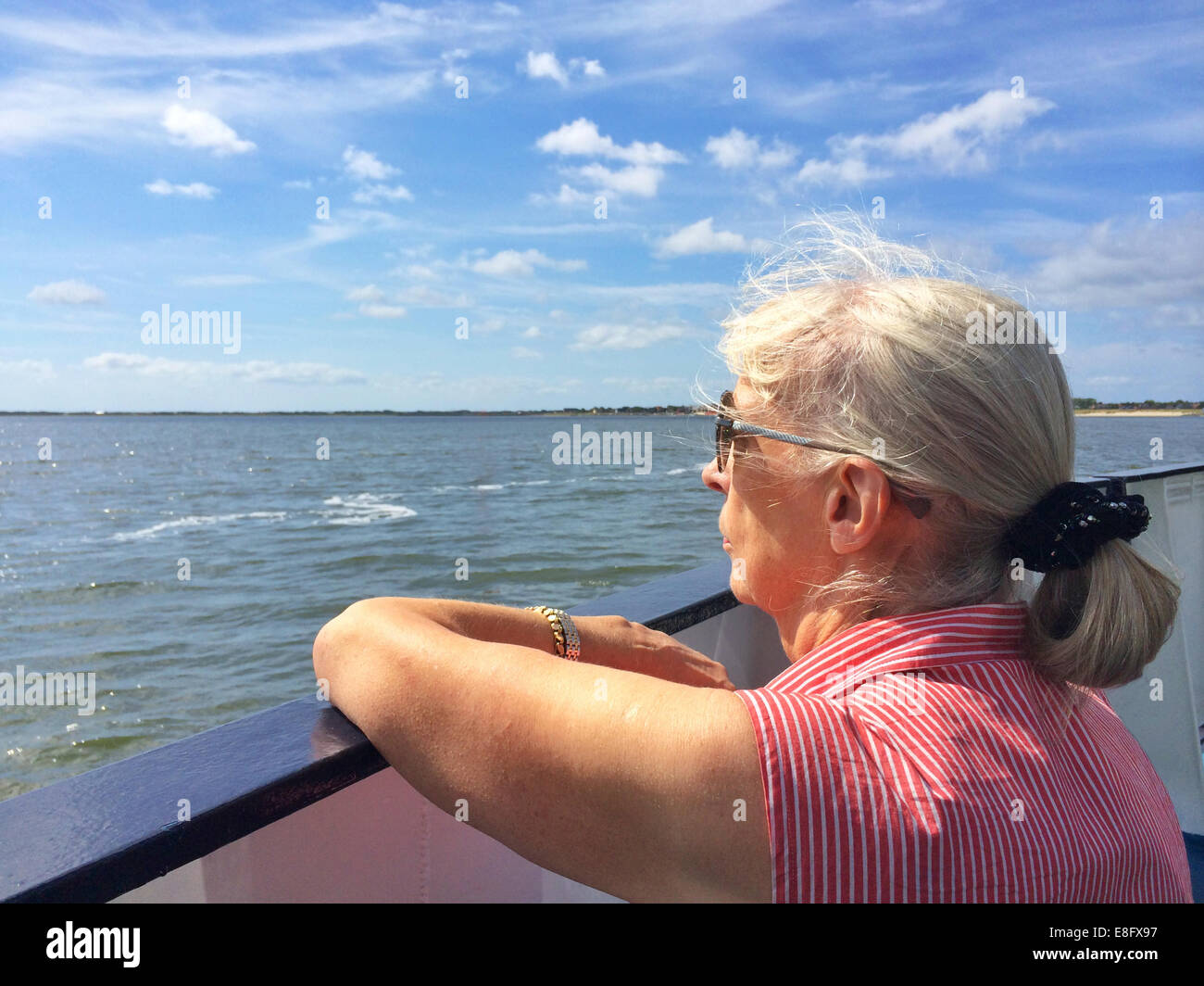 Senior donna sulla barca che guarda al mare Foto Stock