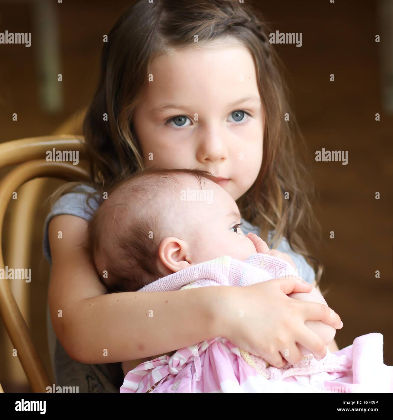 La ragazza (4-5 anni) cuddling baby sorella Foto Stock