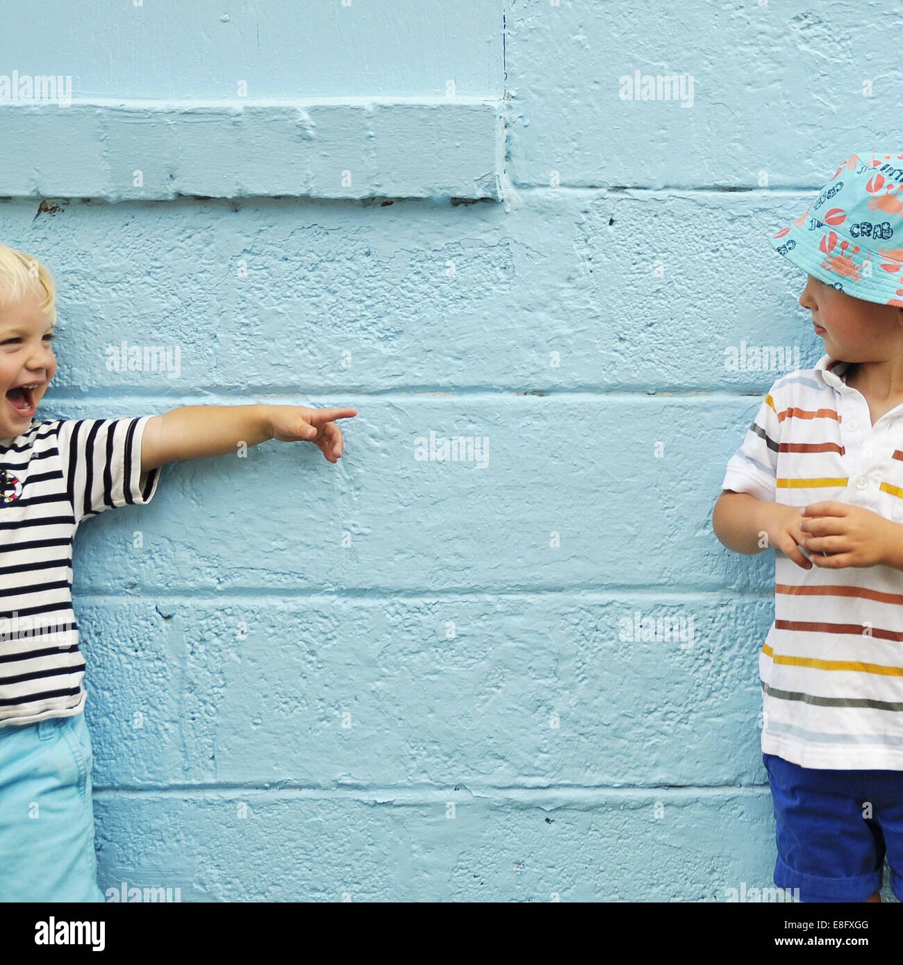 Due ragazzi messing about davanti a una parete blu Foto Stock