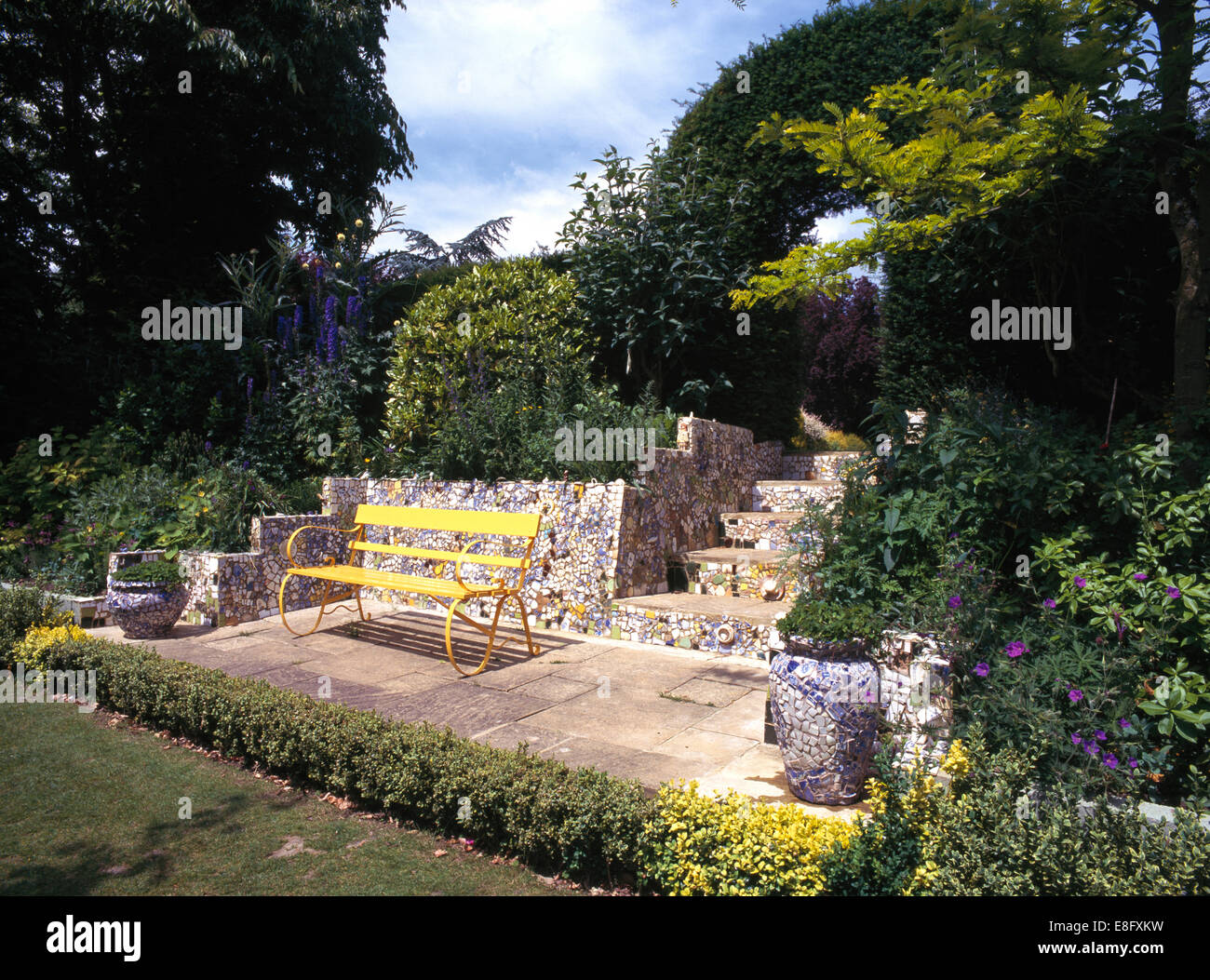 Verniciato giallo panca su patio refilato con bassa copertura ritagliata nel paese grande giardino Foto Stock